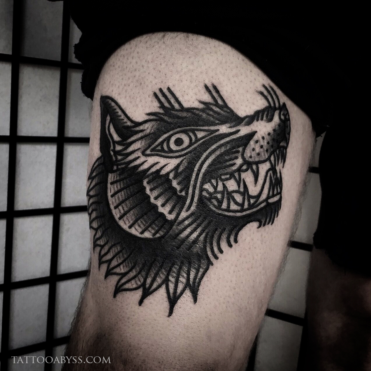 Traditional style wolf head pierced by a dagger tattoo