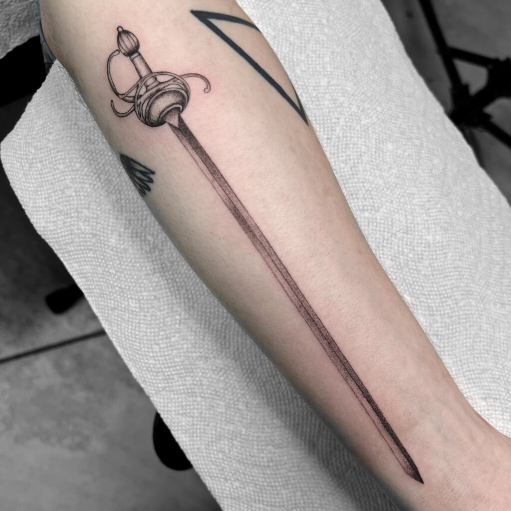 Little sword tattoo located on the inner forearm.